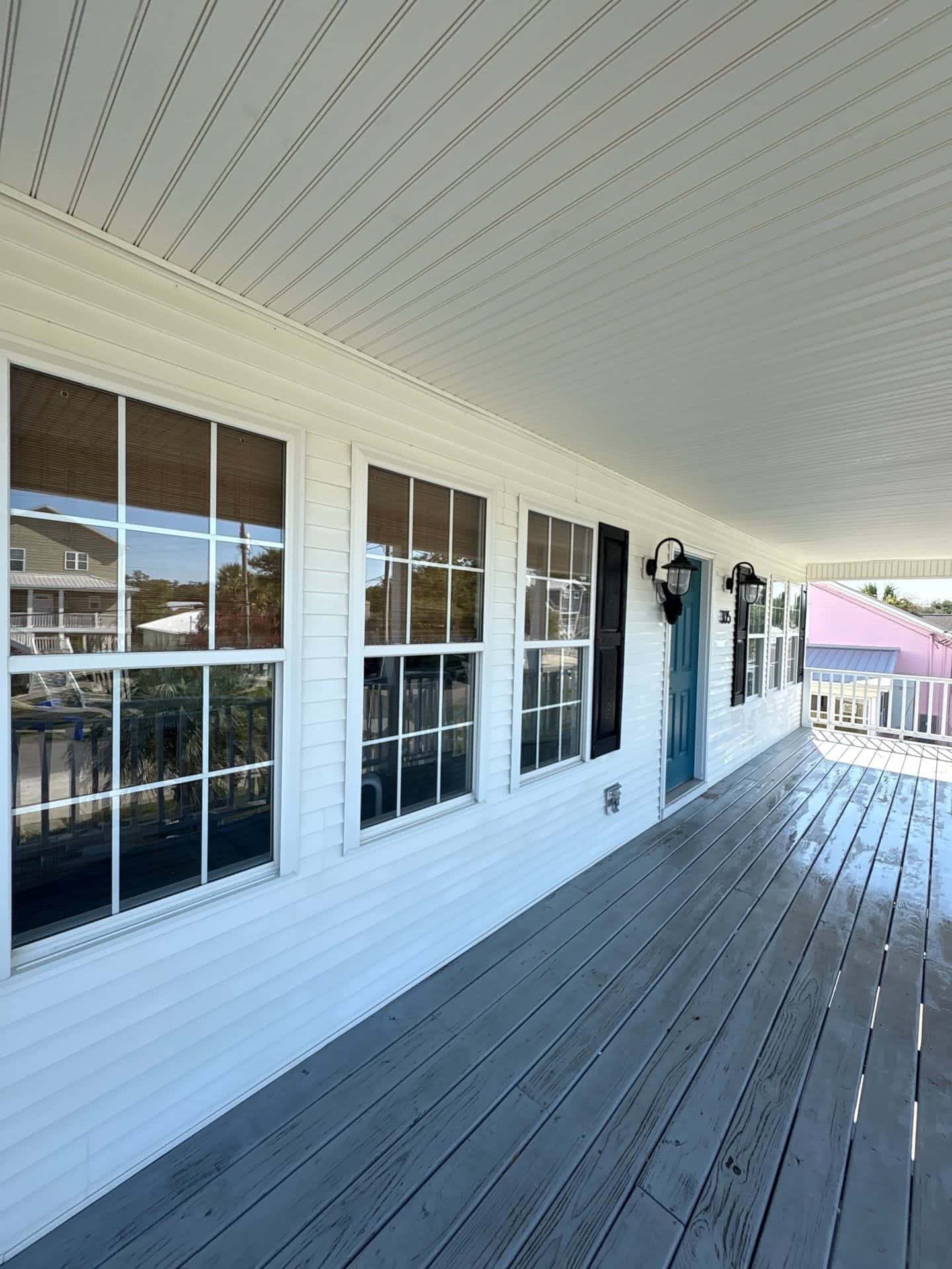 After: Covered porch soft washing before and after in the Wilmington, NC area: siding and windows restored to bright white